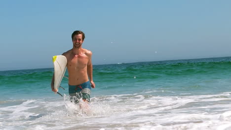 man getting out of water with surfboard