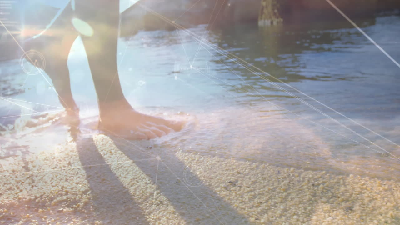 Bare feet walking on sandy beach with digital network overlay animation