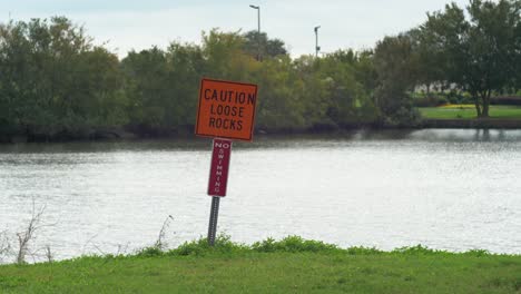 caution loose rocks no swimming sign park pond wide