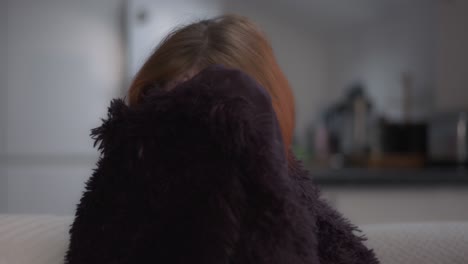 chica asustada viendo una película de terror en el sofá escondiéndose en una manta con el parpadeo de la televisión