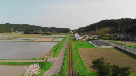 aerial tracking of straight train tracks running through japanese countryside