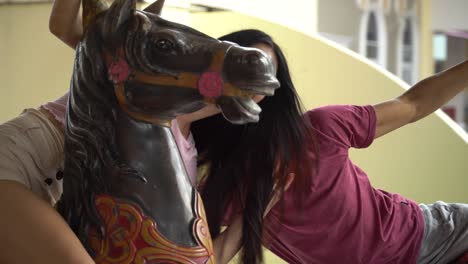 couple in love riding on carousel holding hand and kissing together at the amusement park outdoors in summer having fun in vacation