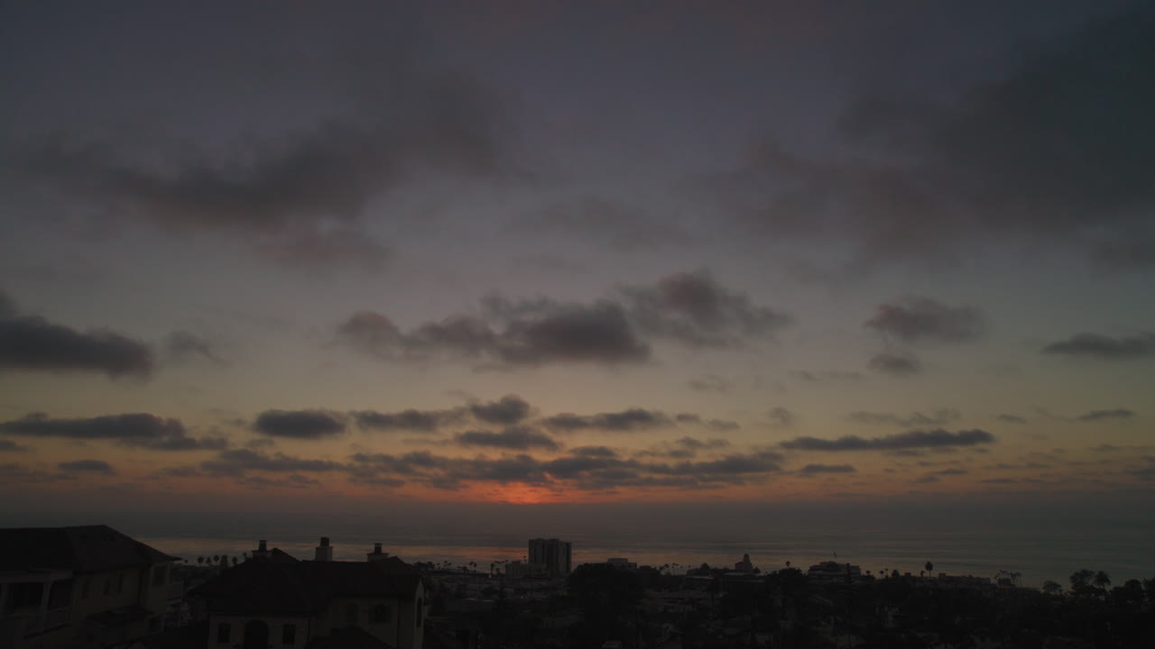 Tomado desde lo alto de una colina con vistas al océano y a la ciudad de La Jolla en San Diego, California, este clip muestra nubes que se acercan lentamente desde el océano mientras el sol se pone tras el horizonte