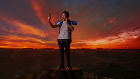 mujer tomando una selfie en la cima de una montaña al atardecer