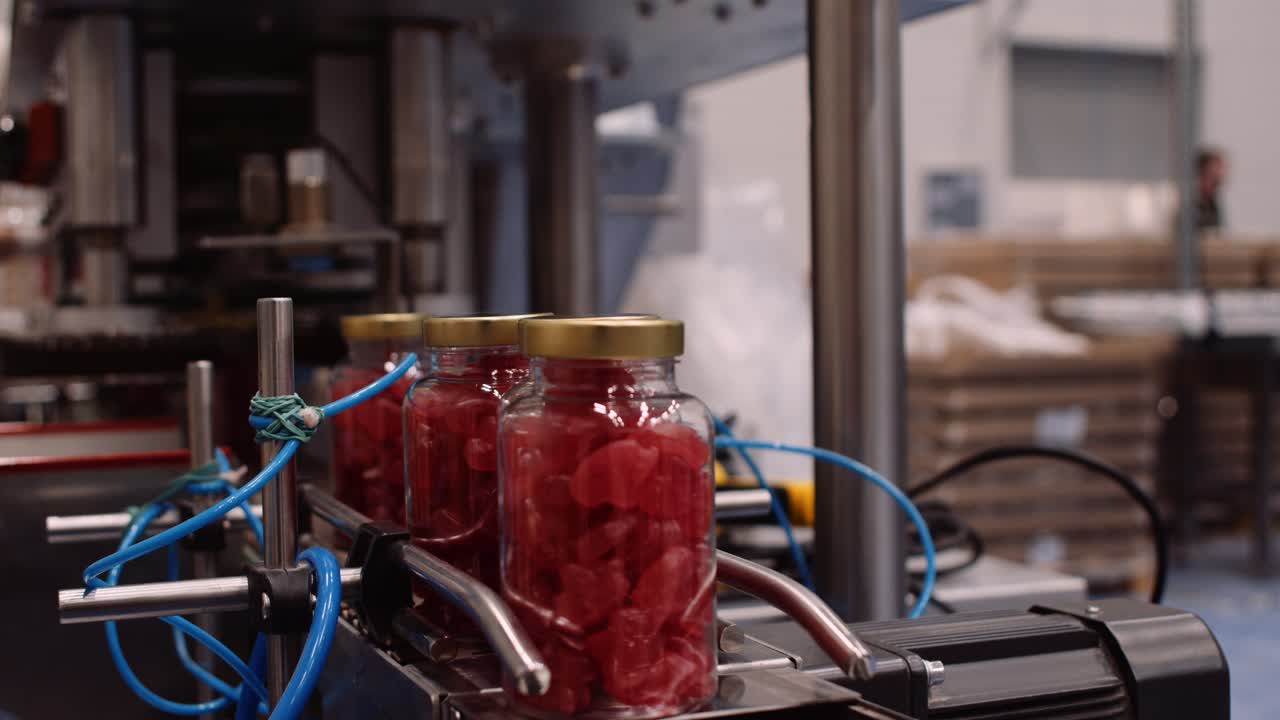 красные поливитаминные добавки в бутылках, движущиеся по конвейеру на заводе