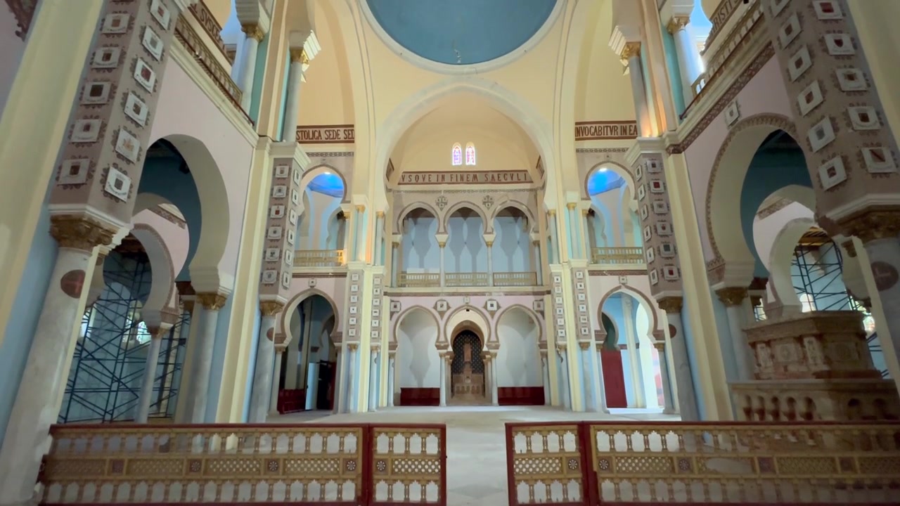 Interno della Cattedrale di San Luigi (Acropolium di Cartagine) con archi, gradini in marmo e un altare vuoto incorniciato da ringhiere decorative. Tunisia.