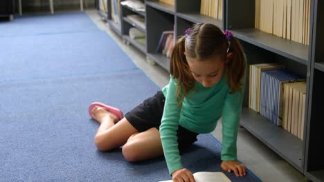 front view of attentive caucasian schoolgirl reading a book in library at school 4k