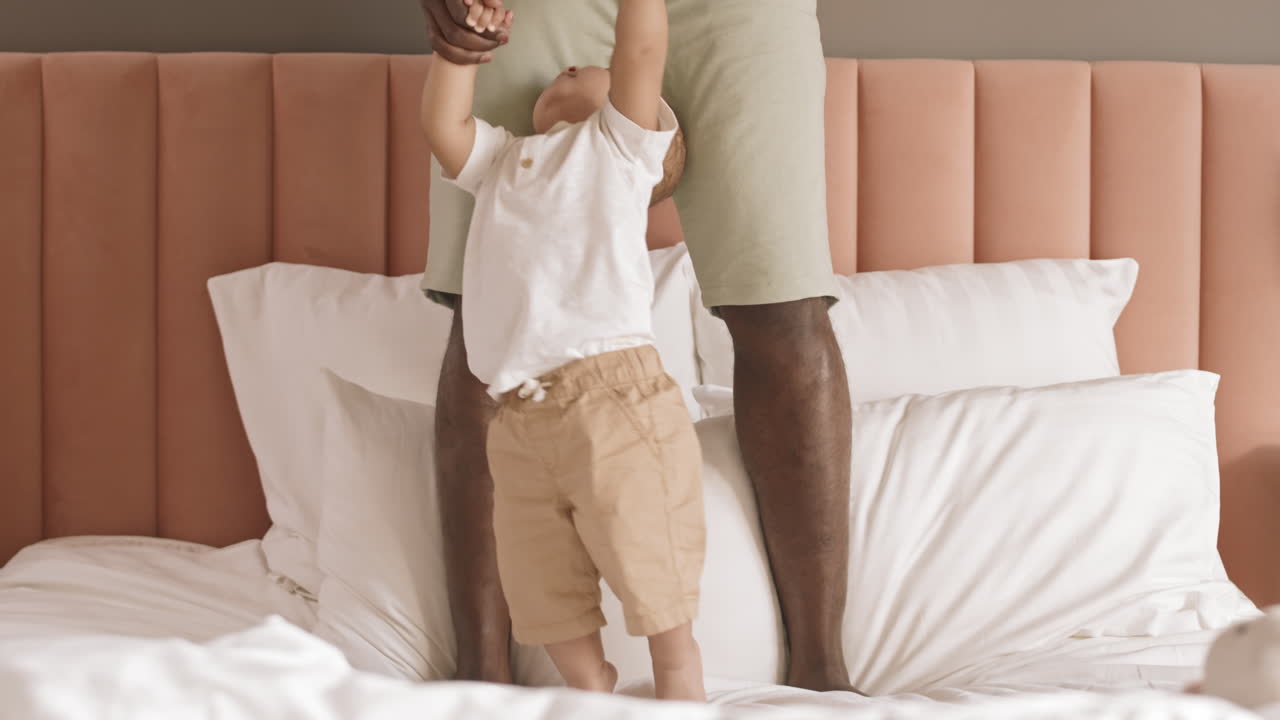 Father Helping Toddler Walking on Bed