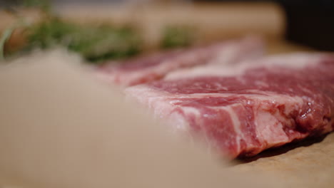 Close-up-of-red-juicy-meat-with-white-fat-veins-on-paper-surface