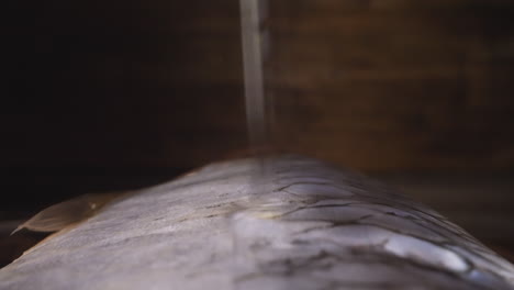 pouring oil onto salted herring back on wooden background