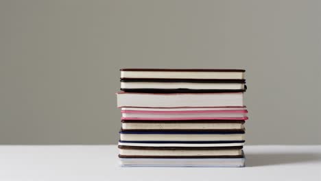 close up of stack of books on grey background, in slow motion