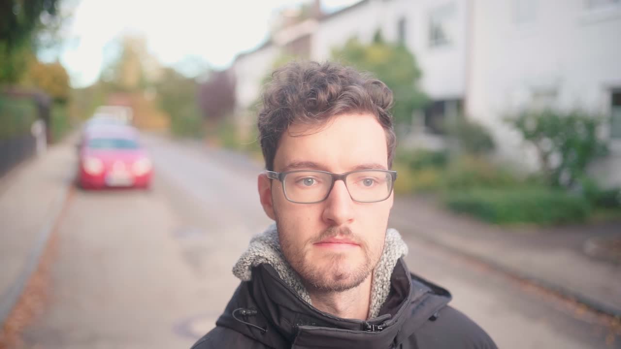 cámara lenta de un joven europeo vagando por los suburbios, vestido cálidamente, encarnando la esencia de un acogedor ambiente de otoño