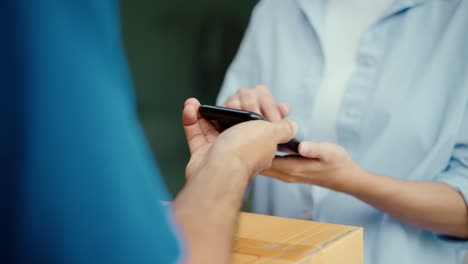 hand woman signing electronic signature on smartphone for agreement of contract digital receiving parcel from blue delivery man from shopping online. courier man delivering package to destination.