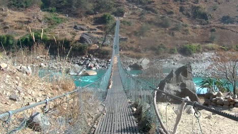 pov walking on a dangerous metal suspension footbridge over gorge in the mountains in nepal