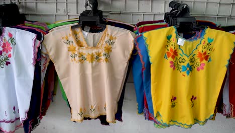 camera moving to right and panning left showing colorful designer huipil blouses indigenous to merida, yucatan, mexico