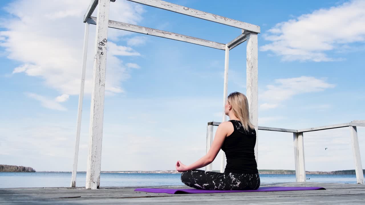 Woman meditating on a lake pier
