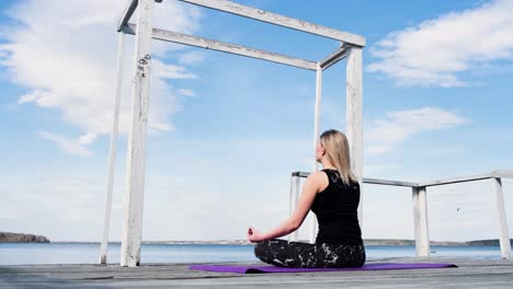 woman meditating on a lake pier