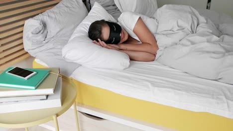 mujer con máscara para los ojos durmiendo en el dormitorio