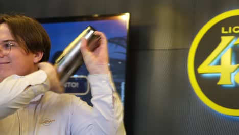 a handsome man joyfully shakes a cocktail with a mixer, exuding enthusiasm and skill as he creates a vibrant drink, smiling throughout the process.