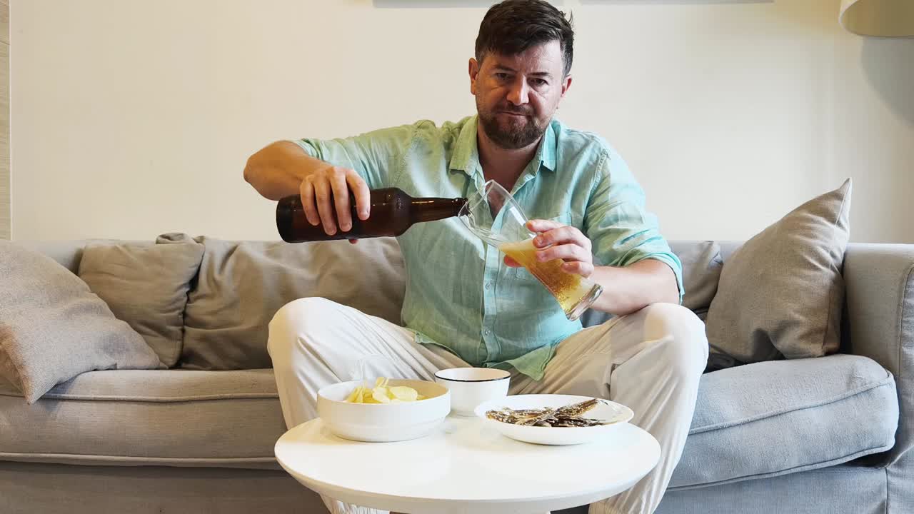 Man Drinking Beer and Eating Snacks on a Couch