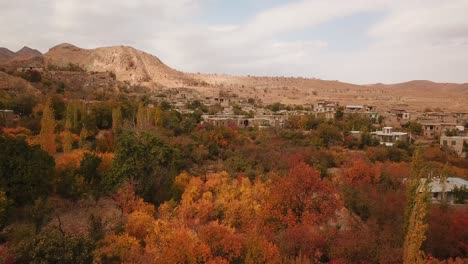 un pueblo rural de otoño en la montaña con hojas amarillas, naranjas, verdes y árboles coloridos y edificios en forma de escalera en la cordillera y las colinas al lado de la granja de campos de azafrán