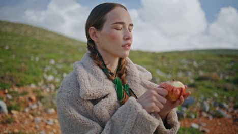 closeup girl peeling apple on green hill. contemplative traveler rest mountains