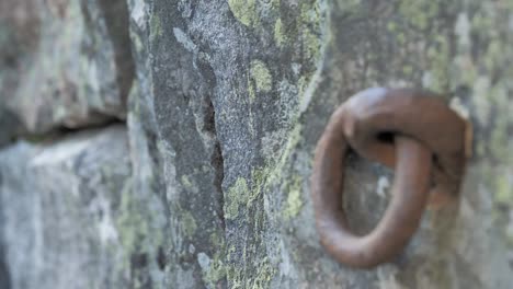 closeup shot of an old granite wall with a rusty loop on it.