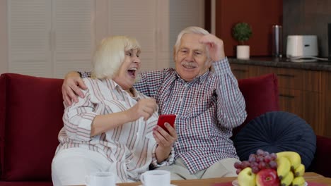 Abuelos-De-Una-Pareja-De-Ancianos-Hablando-Y-Usando-Una-Computadora-De-Teléfono-Móvil-En-Casa.-Compras-Por-Internet