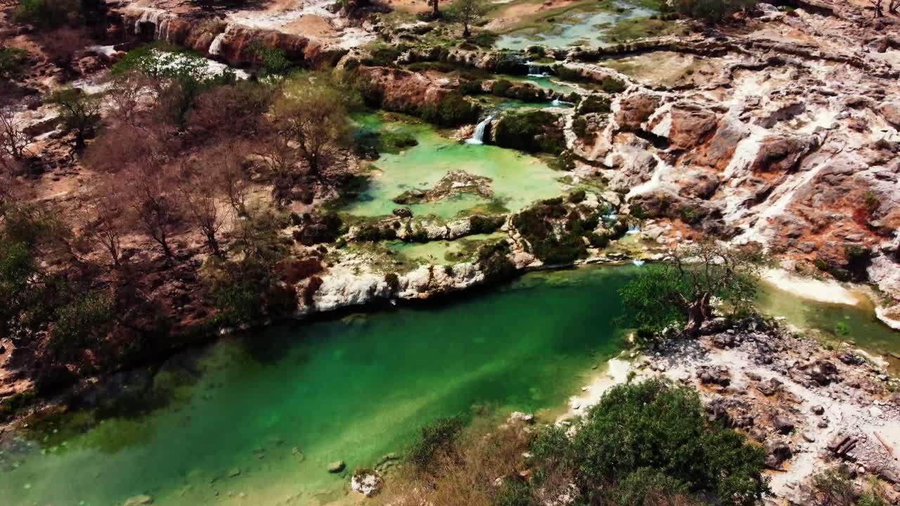 Aerial view of Wadi Darbat, a picturesque valley near Salalah, Oman. Lush greenery and waterfalls await! Watch now!