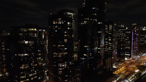 Aerial-drone-backward-moving-shot-of-high-rise-office-and-residential-buildings-at-night-time-in-Chicago,-USA-during-October