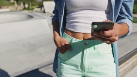 sección media de una mujer caucásica usando un teléfono inteligente en un día soleado