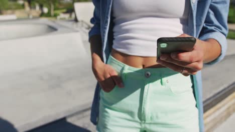 mid section of caucasian woman using smartphone on sunny day