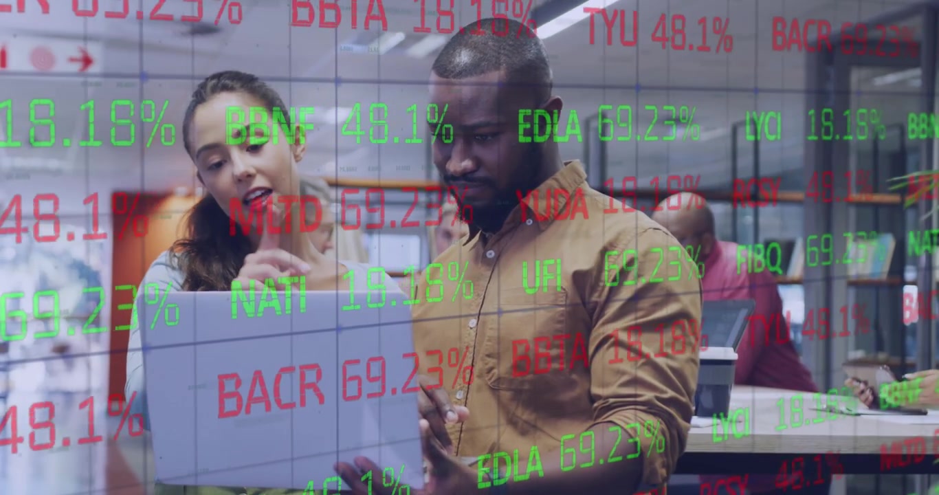A group of male and female colleagues are talking and working on laptops in a modern office