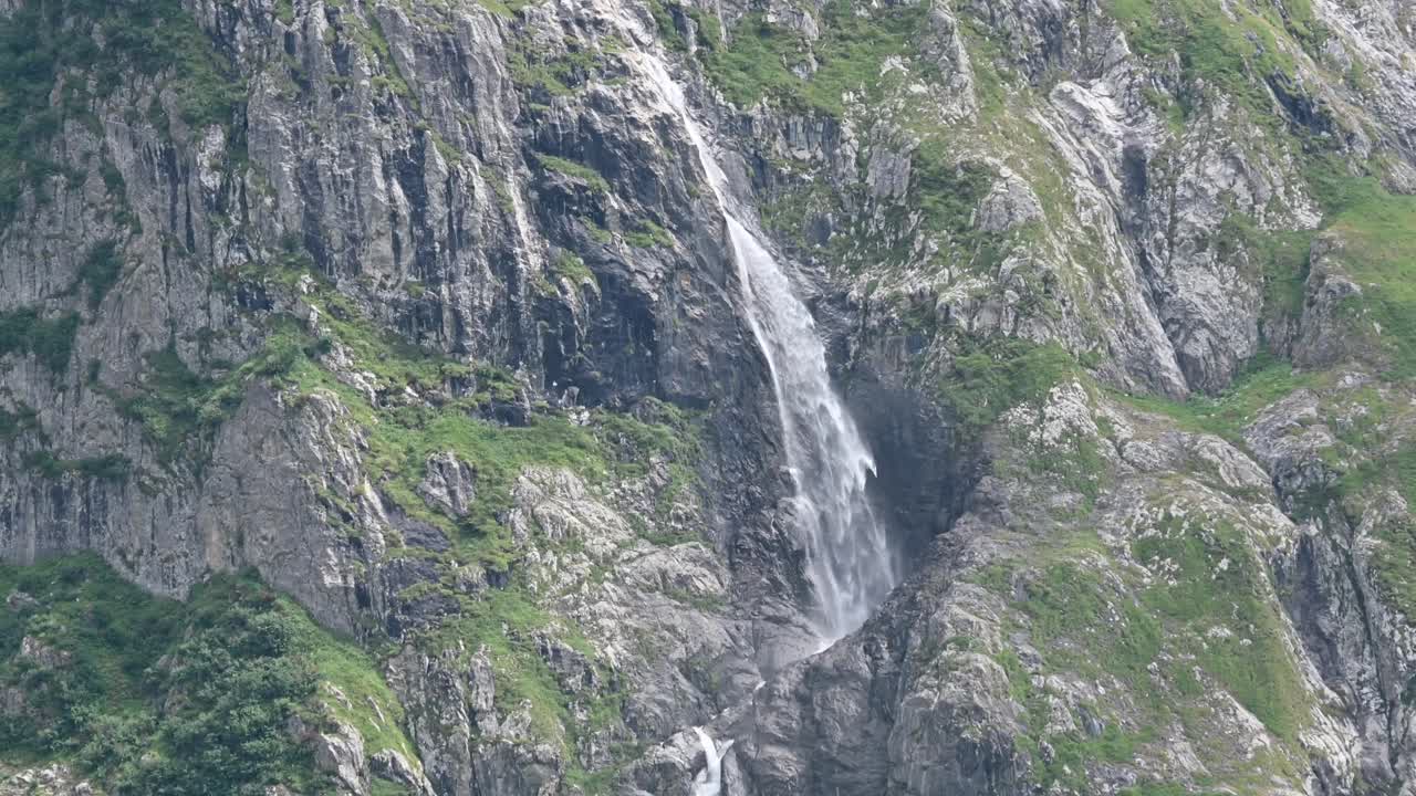 amplia vista de la ladera de una montaña rocosa, fachada, una cascada fluye por la montaña
