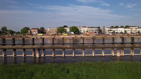 sideways aerial movement following wooden jetty construction leading to steel draw bridge for cargo vessels and boats pass underneath with tower town zutphen countenance in the background
