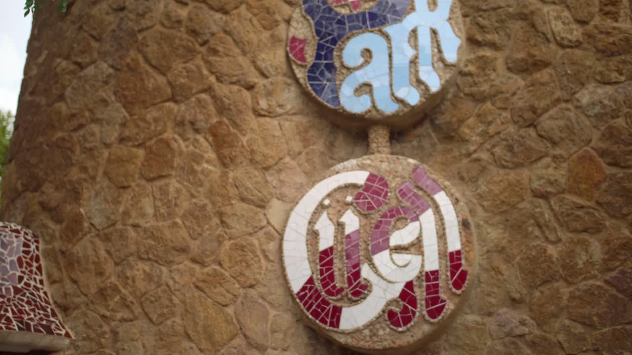 turista tomando una foto del logo del parque guell usando un smartphone en barcelona, españa - toma de mano