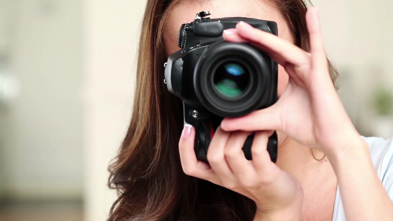 Giovane donna che tiene e regola una fotocamera reflex professionale