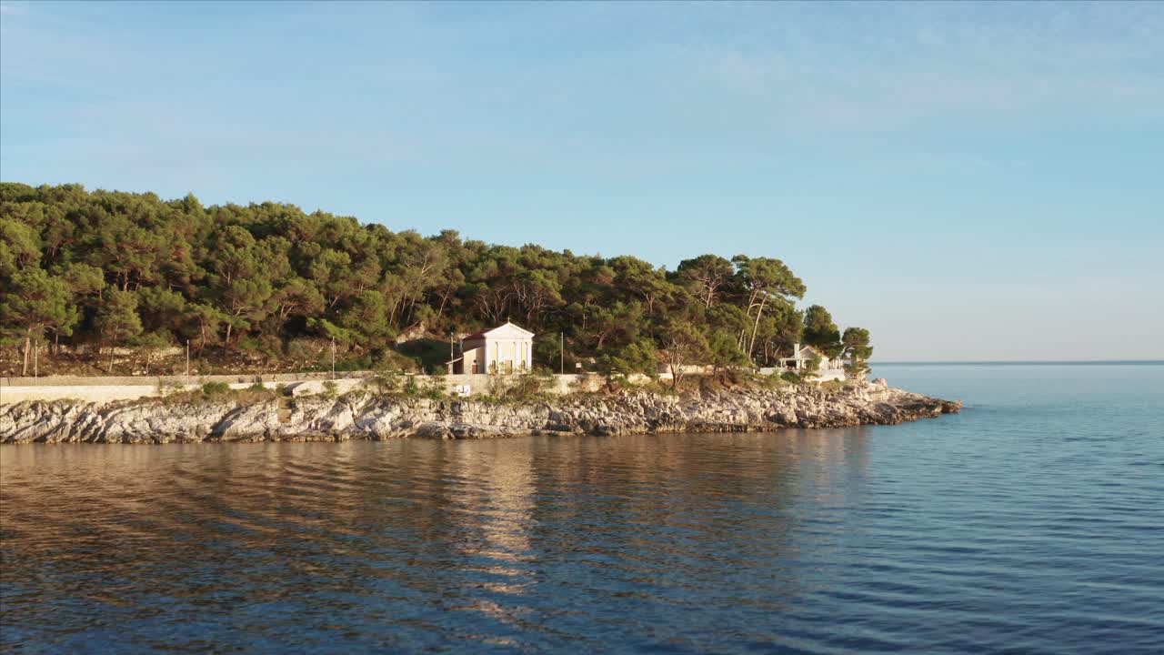 Carrellata aerea sull'acqua che sale e passa sopra una casa a Lussino, Croazia, durante il giorno.