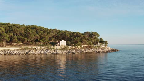 Dolly-Aéreo-Disparó-Sobre-El-Agua-Tirando-Hacia-Arriba-Y-Sobre-Una-Casa-En-Losinj,-Croacia-Durante-El-Día