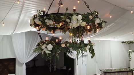 circling a beautiful wedding chandelier covered in flowers and leaves