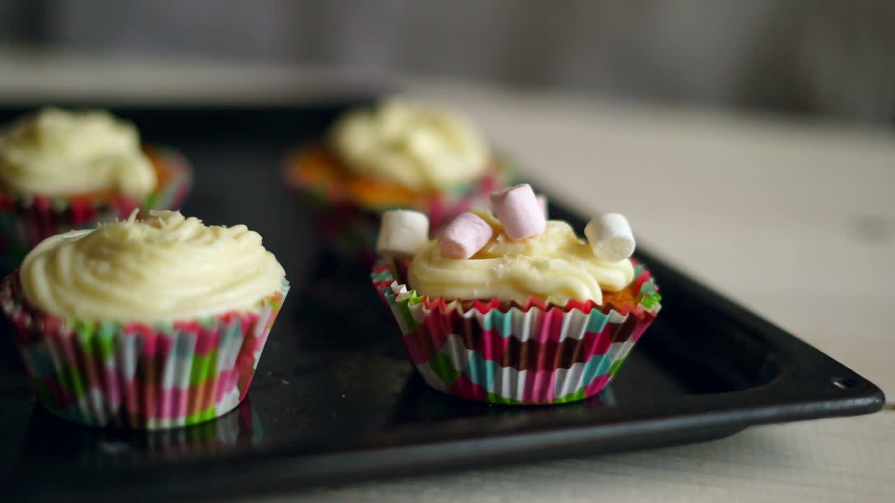 Marshmallow candies falls to muffin. Decorating cupcake