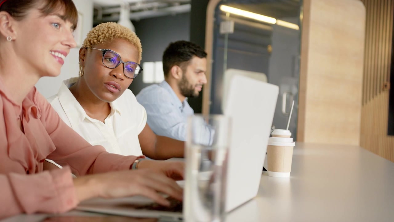 Coworkers typing on laptops in tech hub, input causing chat bubble expanding fading, alerting team