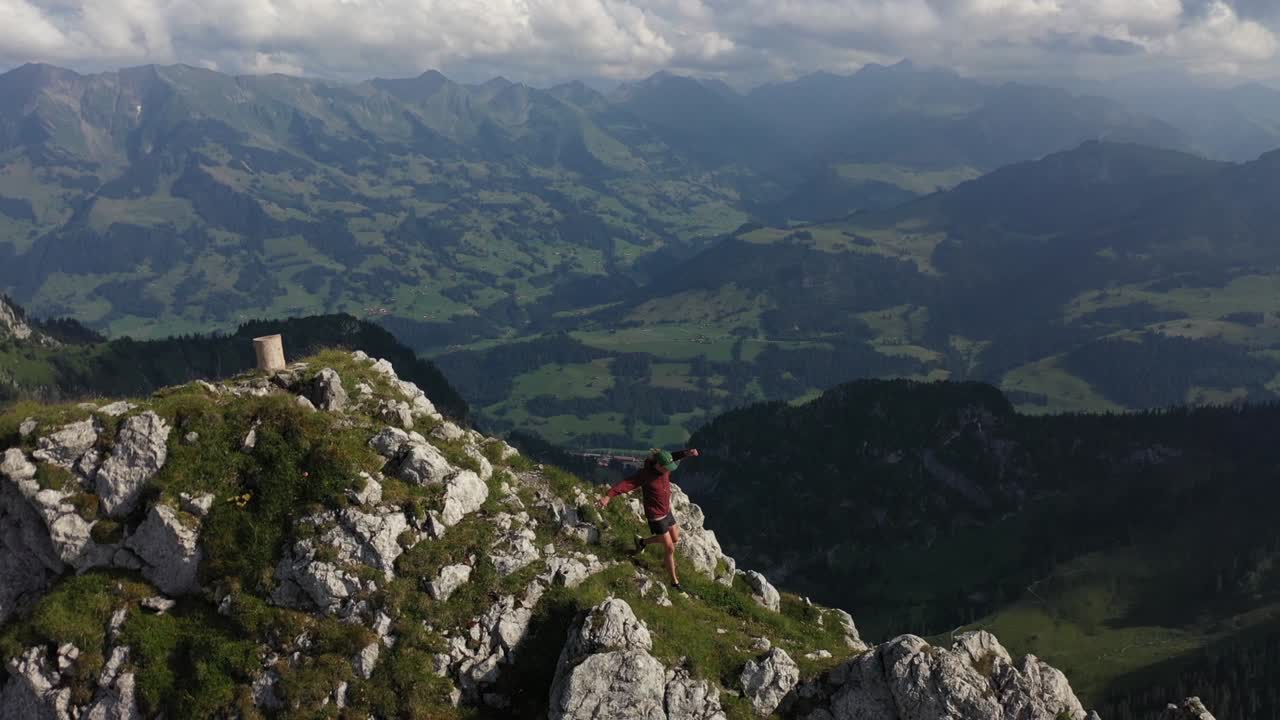 toma de seguimiento de un dron de un joven corriendo y saltando por un sendero estrecho en el borde