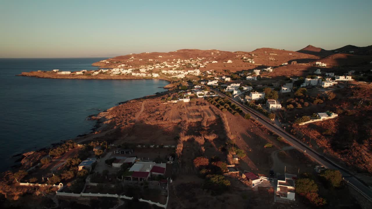 camiones drone pan a lo largo de las villas costeras y casas en la hora dorada puesta de sol, largas sombras en siros grecia