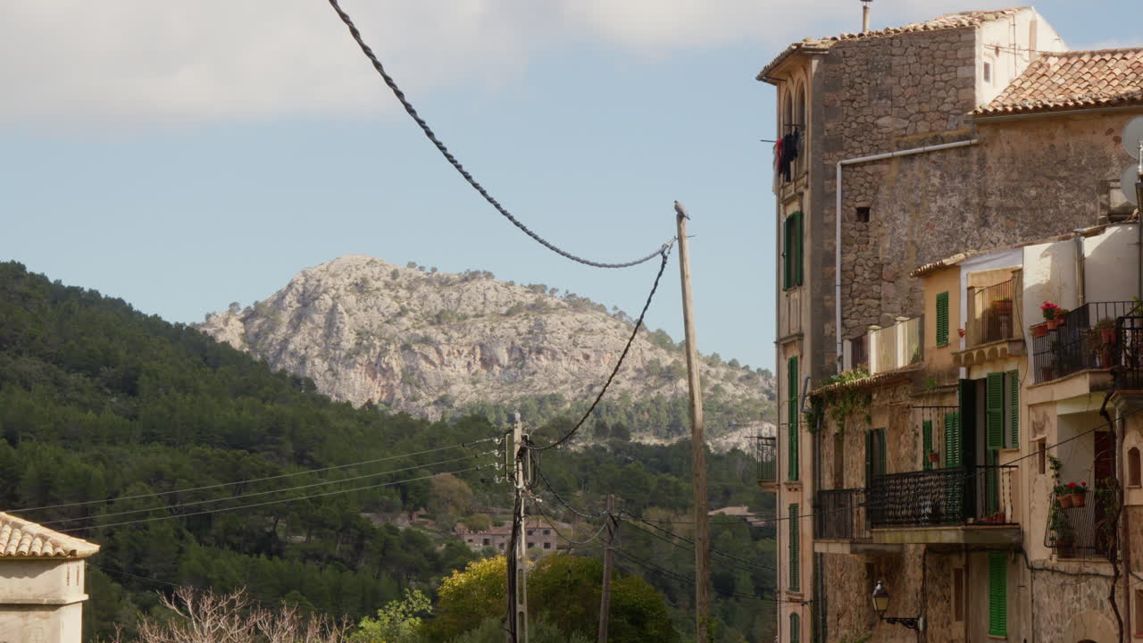 Una vista incantevole di Valldemossa, Maiorca, Spagna, con montagne sullo sfondo e vecchie case che costeggiano la strada.