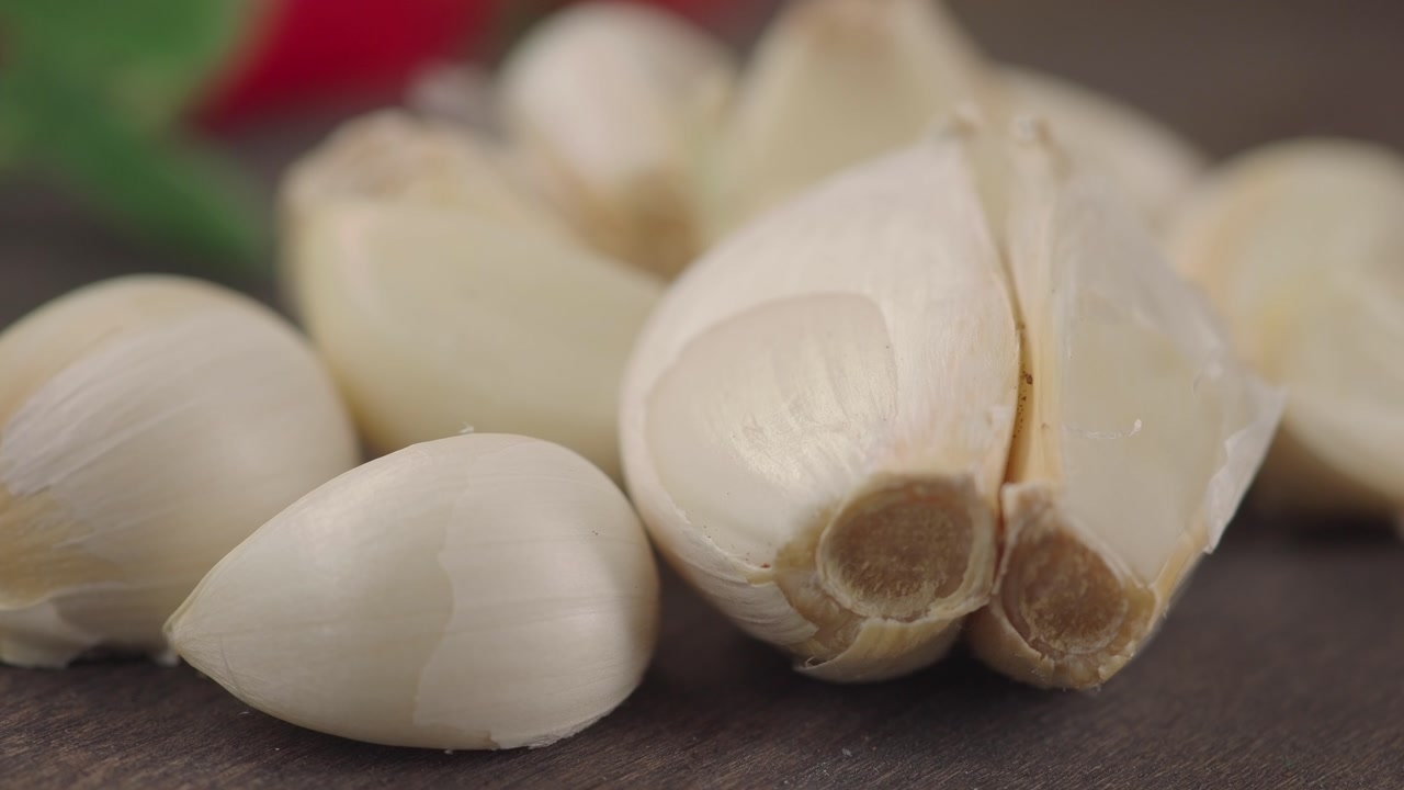 Peeled Garlic Cloves and Split Bulb on Wooden Surface