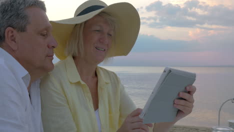 senior couple using touch pad at the seaside