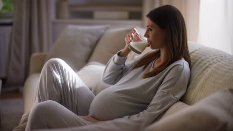 pregnant woman relaxing on a couch and drinking milk