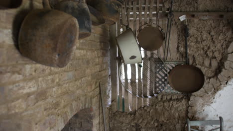 Rustic-kitchenware-hangs-against-an-old-brick-wall,-with-an-antique-feel,-suitable-for-historical-and-culinary-themes