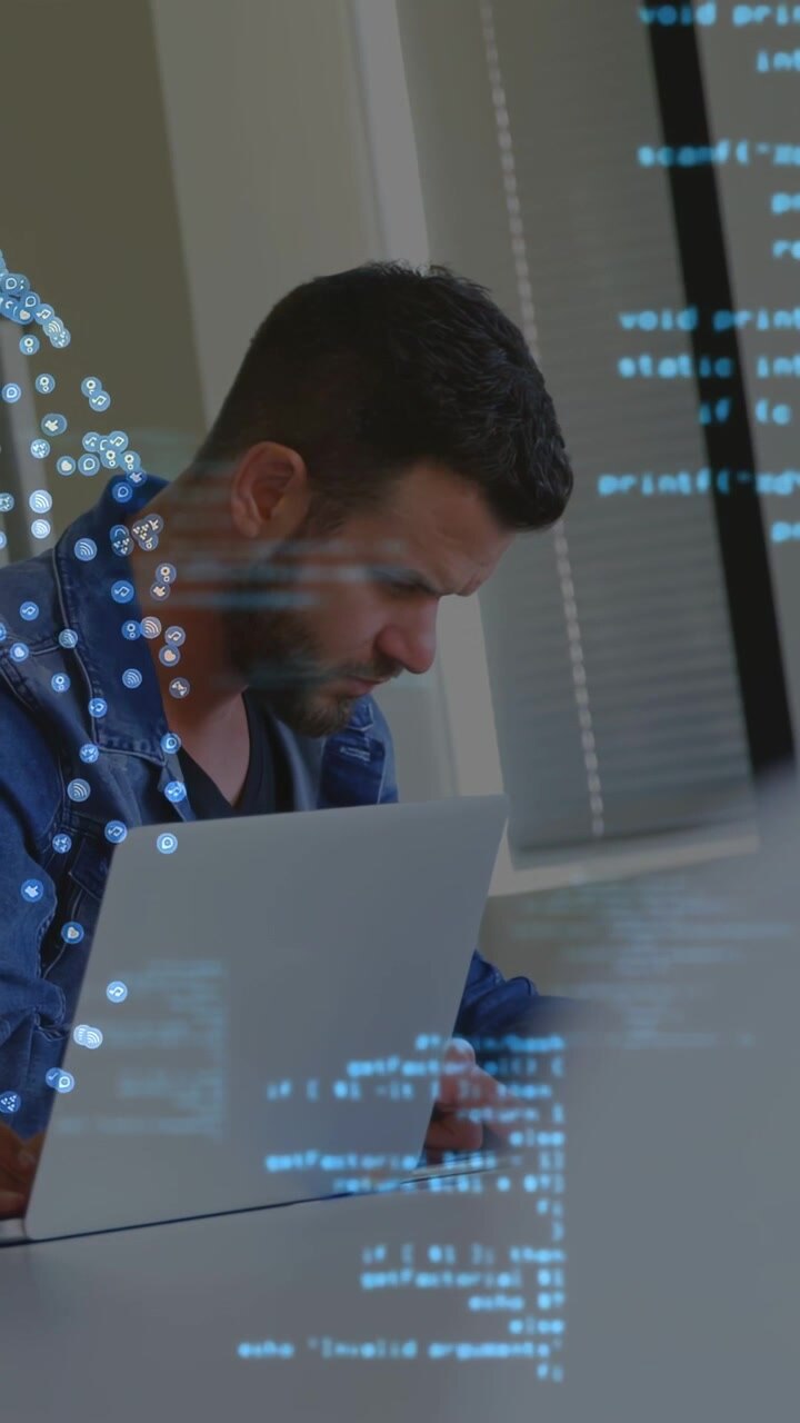 Vertikales Video: Mann tippt im Tech-Büro, überprüft Code unter schwebendem Overlay.